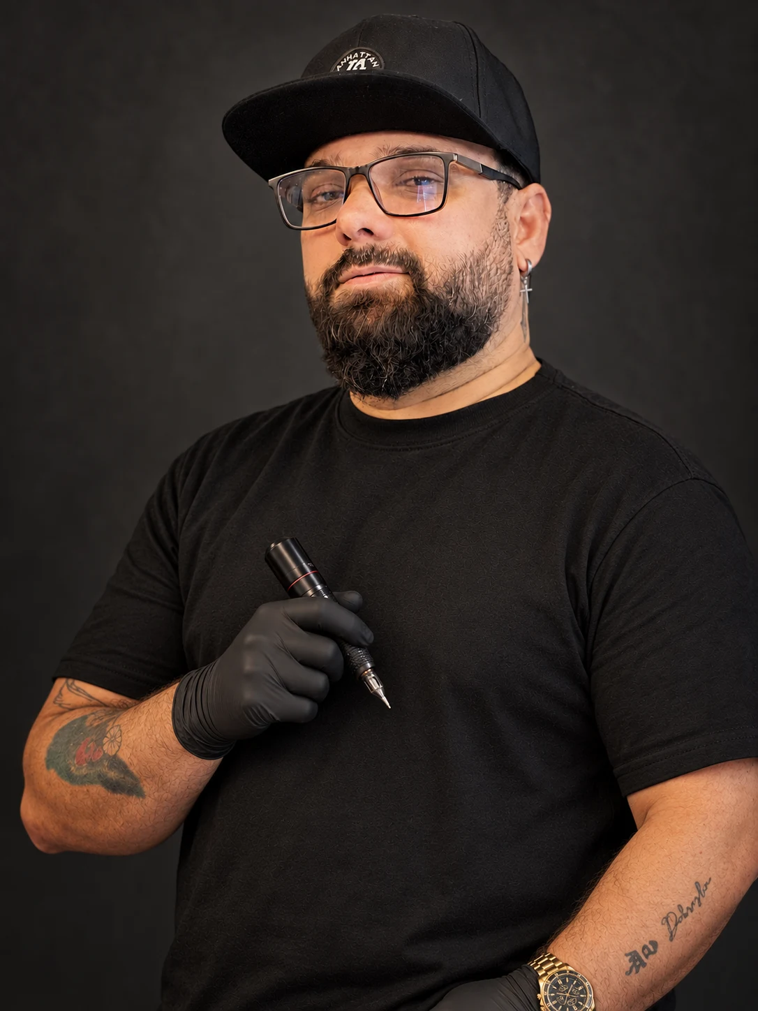 Retrato editorial de Luis Vel con gorra, guantes negros y máquina de tatuar