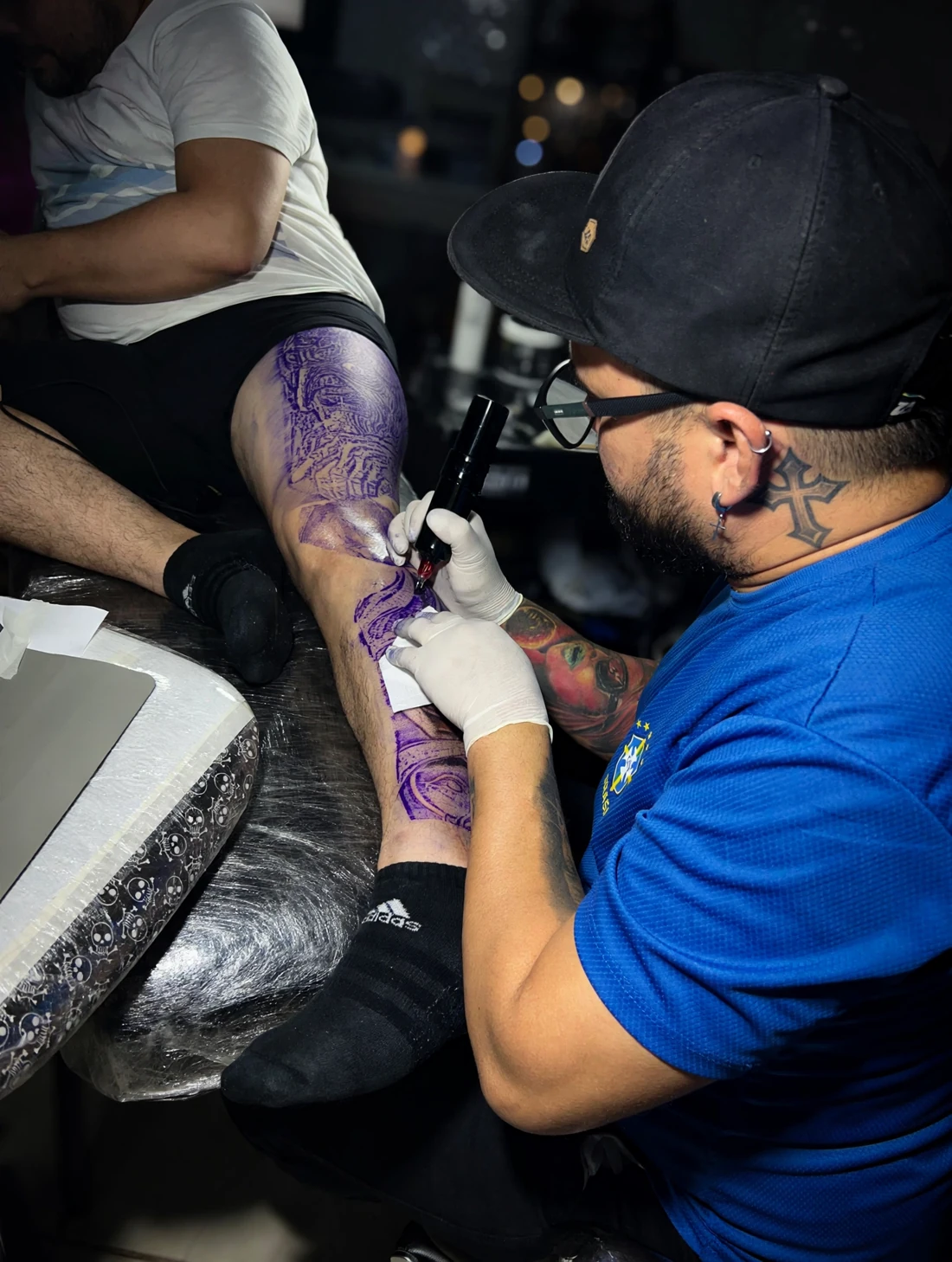 Luis tatuando una pierna durante una sesión, con el diseño transferido sobre la piel